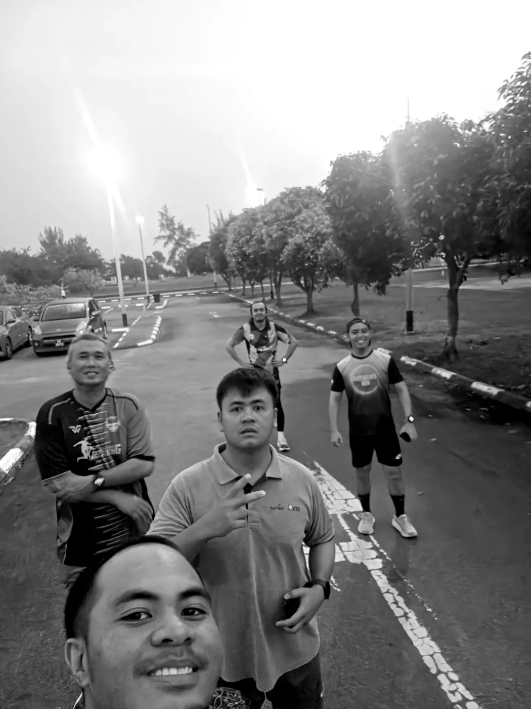 Six runners from the crew smiling for a selfie on a lamp-lined road at dawn