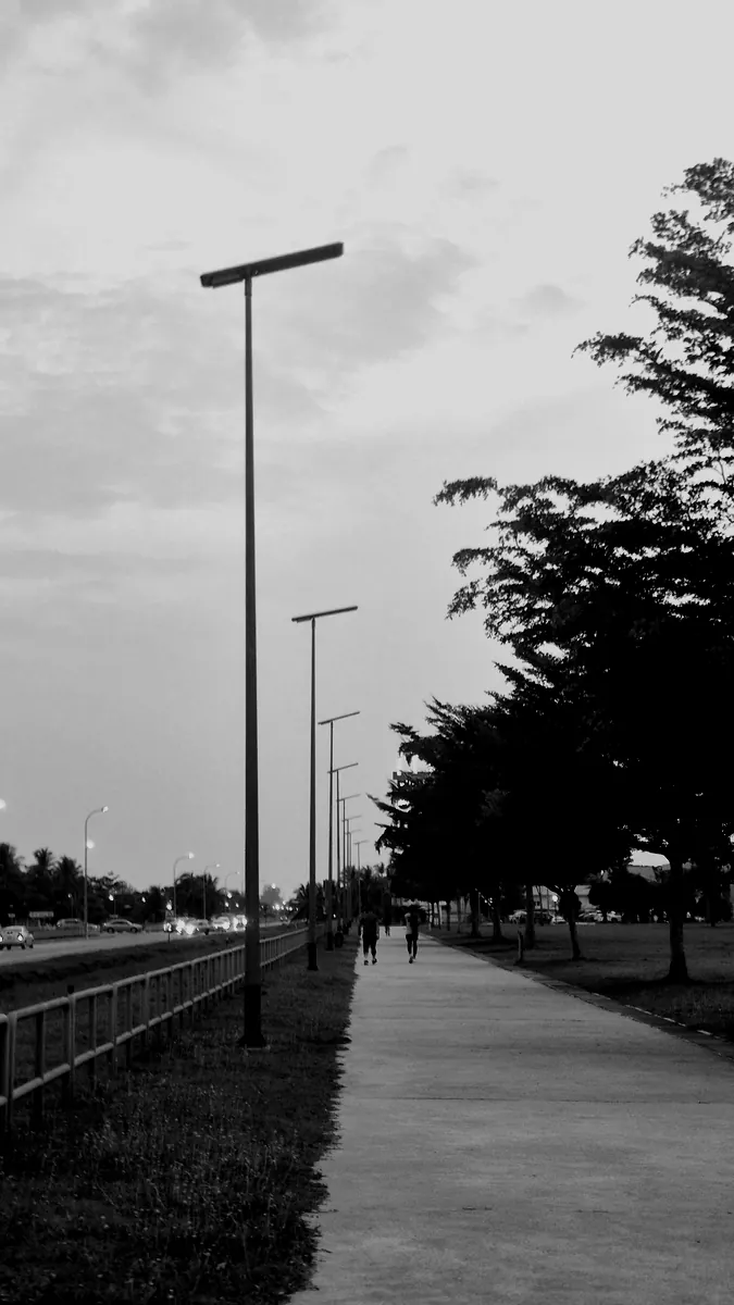 Runners on a lamp-lined path at dusk in Kuala Belait