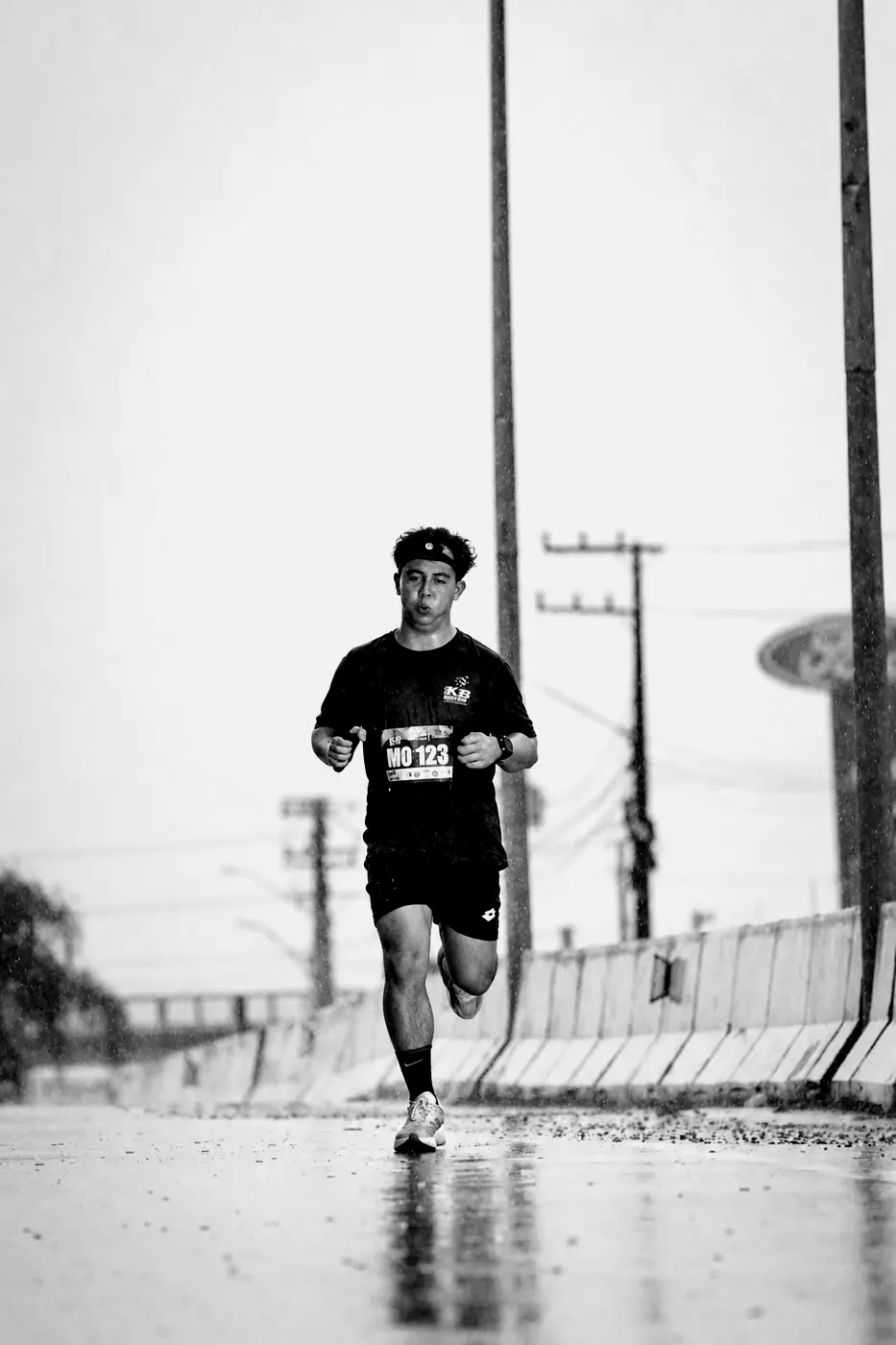 A crew runner running alone through rain on a wet road